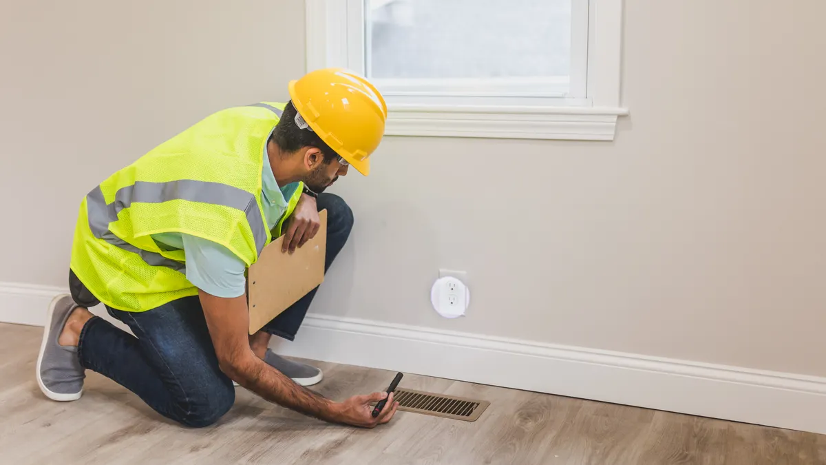 HVAC technician checking a floor vent