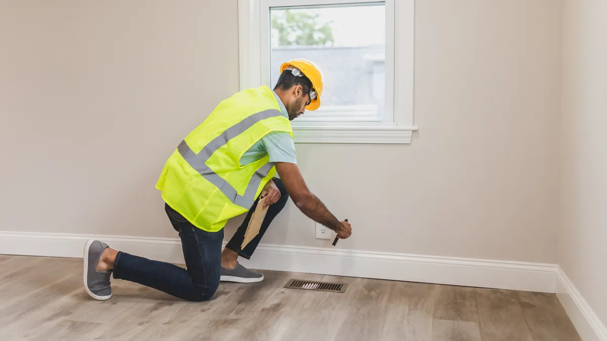 How to choose the right HVAC system size for your home HVAC technician measuring a floor vent in a room