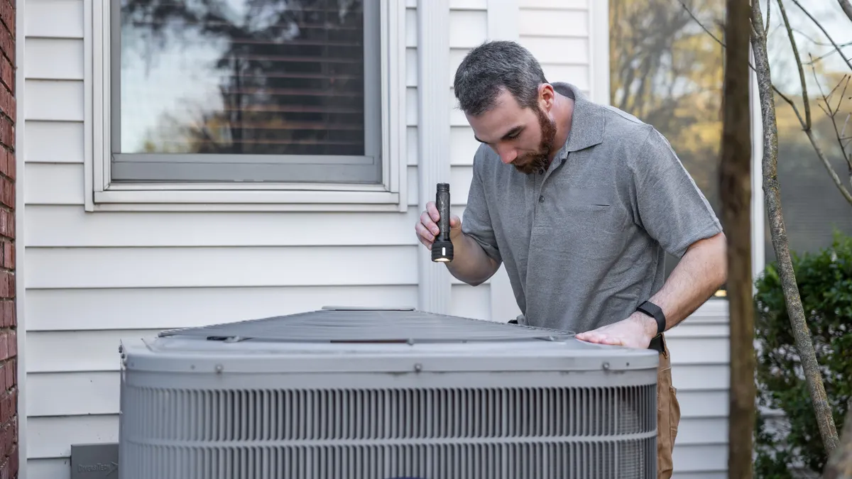 Technician inspecting an outdoor HVAC condenser unit