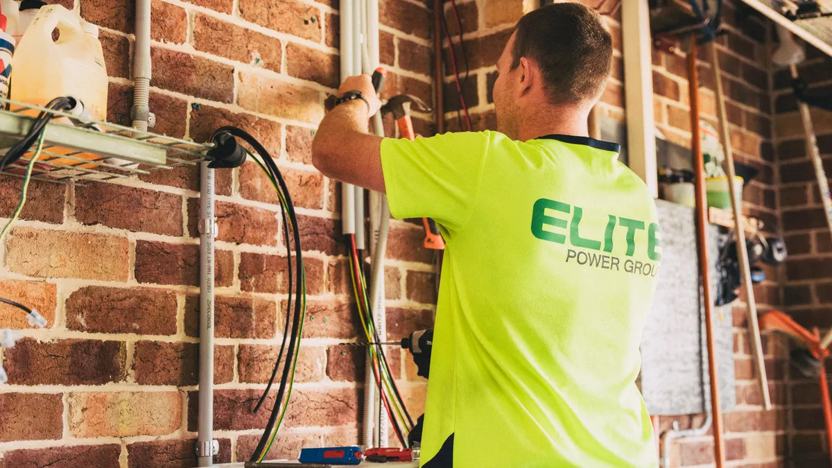 Worker installing HVAC equipment on a brick wall